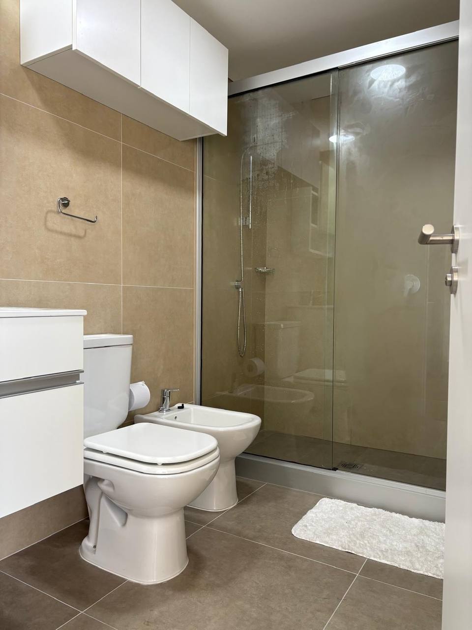 Baño con inodoro, bidet, ducha y azulejos