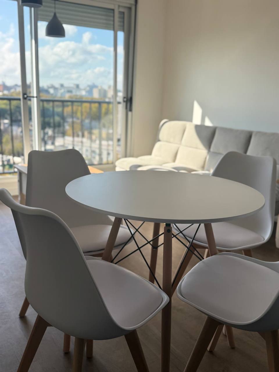 Detalle de mesa, sillas y el living con vista desde adentro