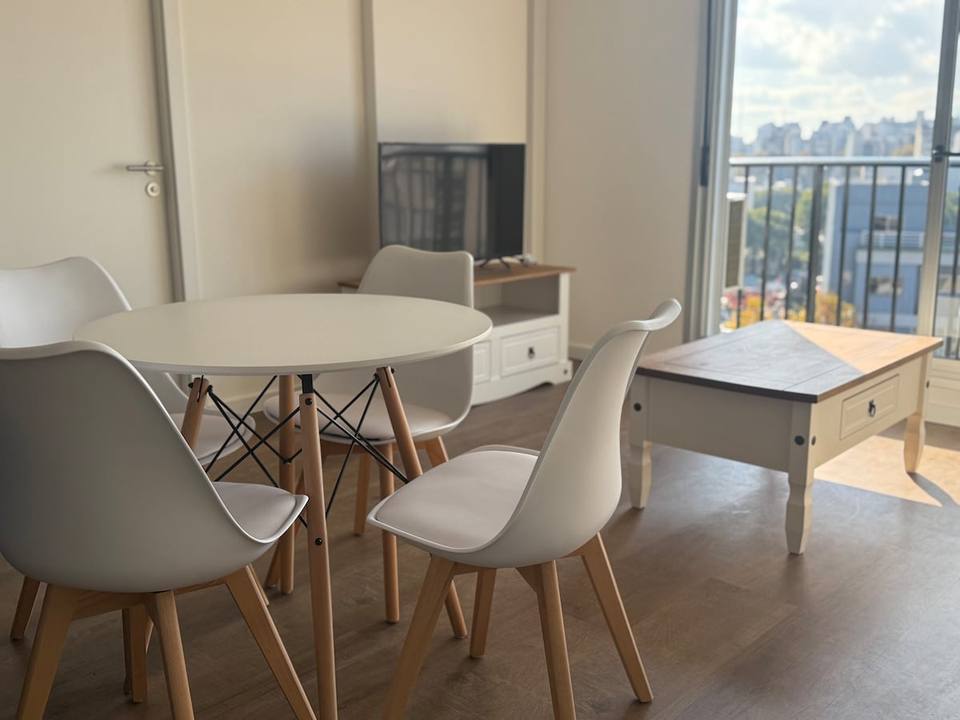 Living con mesa, sillas, tele y sillón, vista al balcón