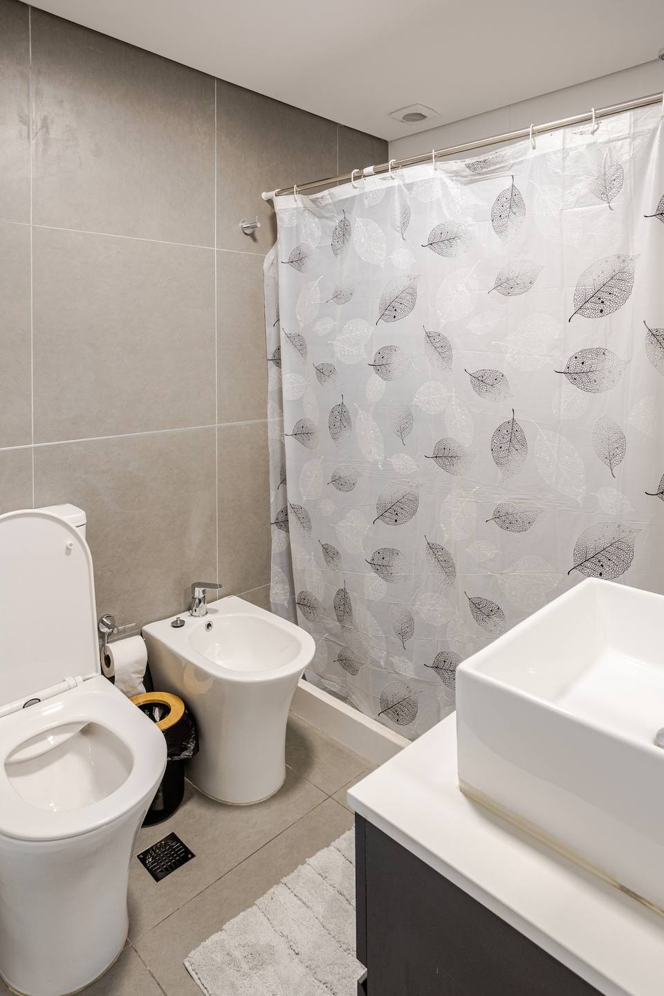 Inodoro, bidet y bañera con cortina en el baño