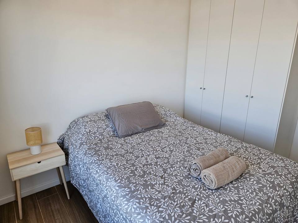 Cama doble con velador, toallas y placard empotrado