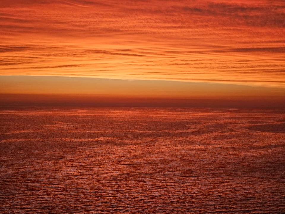 Mar y cielo en tonos de atardecer, rojizos y anaranjados