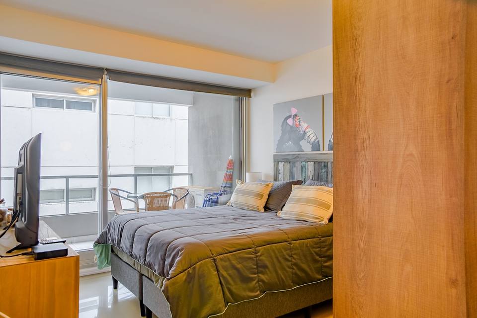 Dormitorio principal con TV y salida al balcón